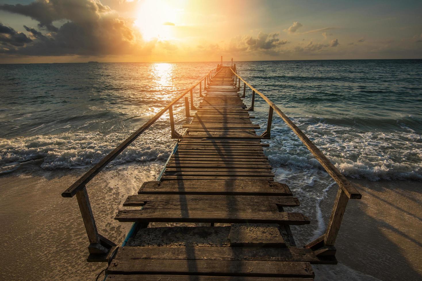 geweldig tropisch zandstrand met silhouet houten brug uit het strand tropisch - promenade of houten loopbrug naar de horizon op zee oceaan paradijs landschap, zonsopgang of zonsondergang zee dramatische lucht foto