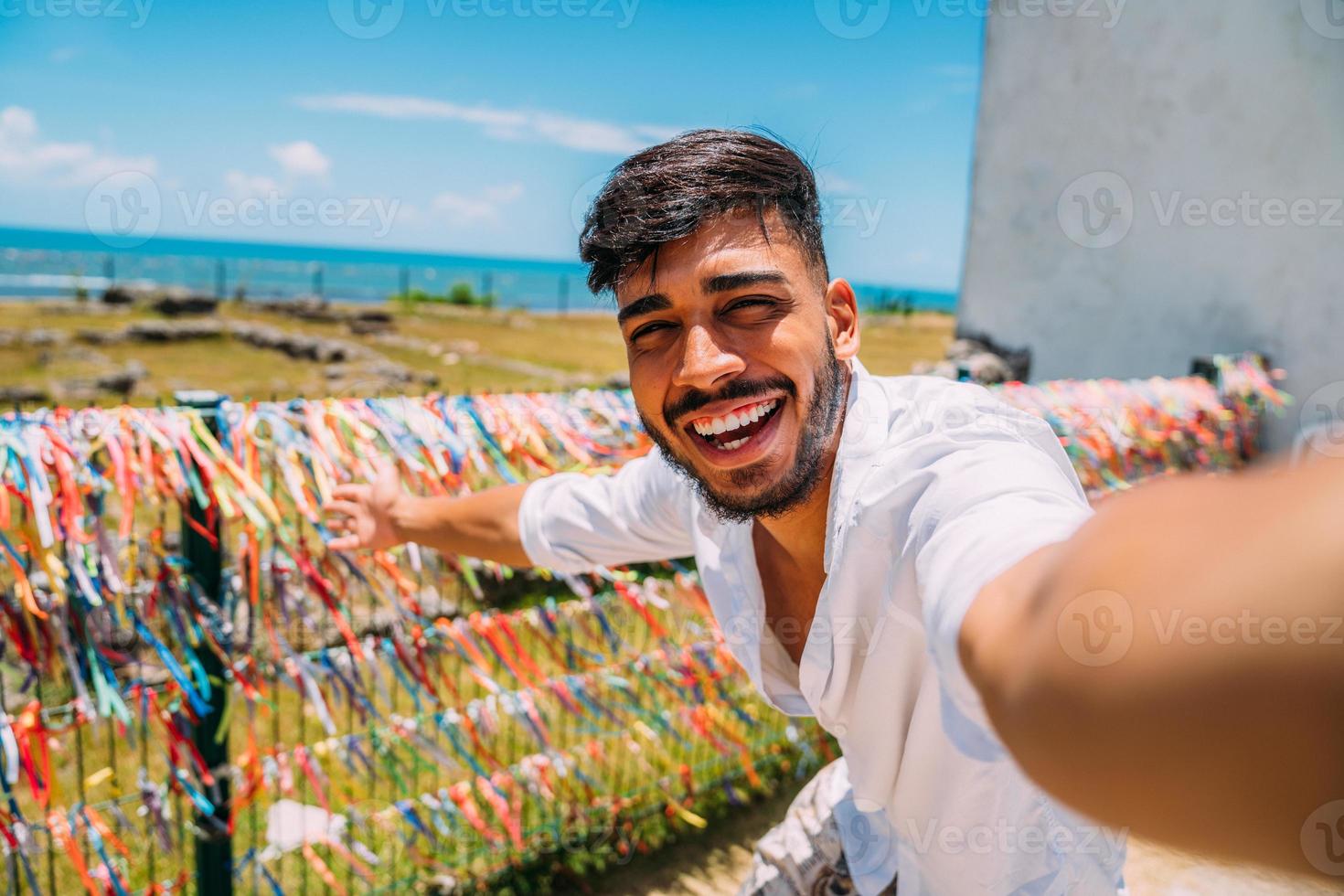 vriendelijke jonge Latijns-Amerikaanse man die uitnodigt om naar Brazilië te komen, zelfverzekerd en glimlachend, een gebaar makend met zijn hand, positief en vriendelijk zijnd foto