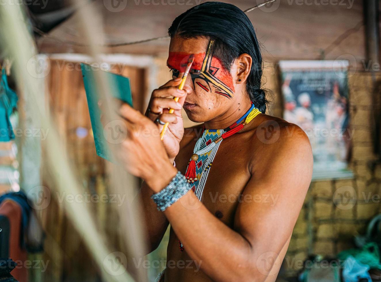 indiaan van de pataxo-stam, met behulp van een spiegel en schminken. foto