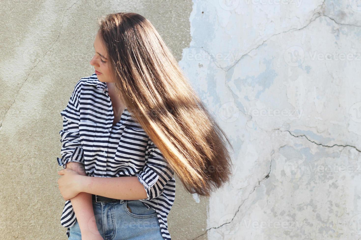 een meisje met lang donker haar dat wappert in de wind, een meisje in een matrozenhemd foto