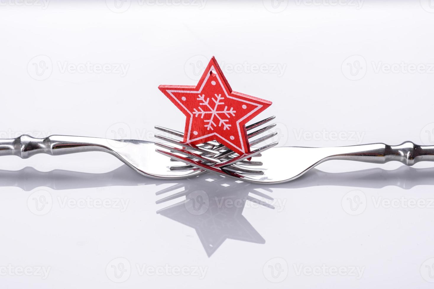 een kleine kerstboomversiering op twee vorken op een witte achtergrond foto