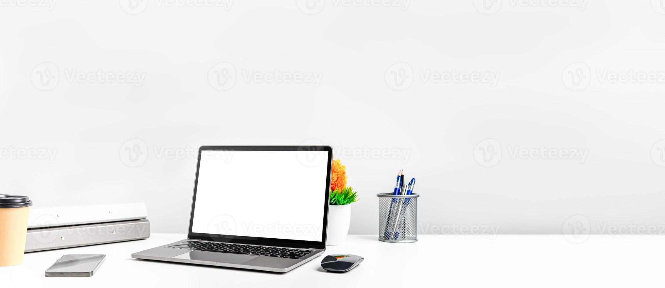 kopieer ruimte aan de rechterkant voor ontwerp of tekst. werkconcept met behulp van technologie smartphones, notebook, internet. leeg wit scherm laptop op witte tafel in het kantoor. close-up, grijze en onscherpe achtergrond foto