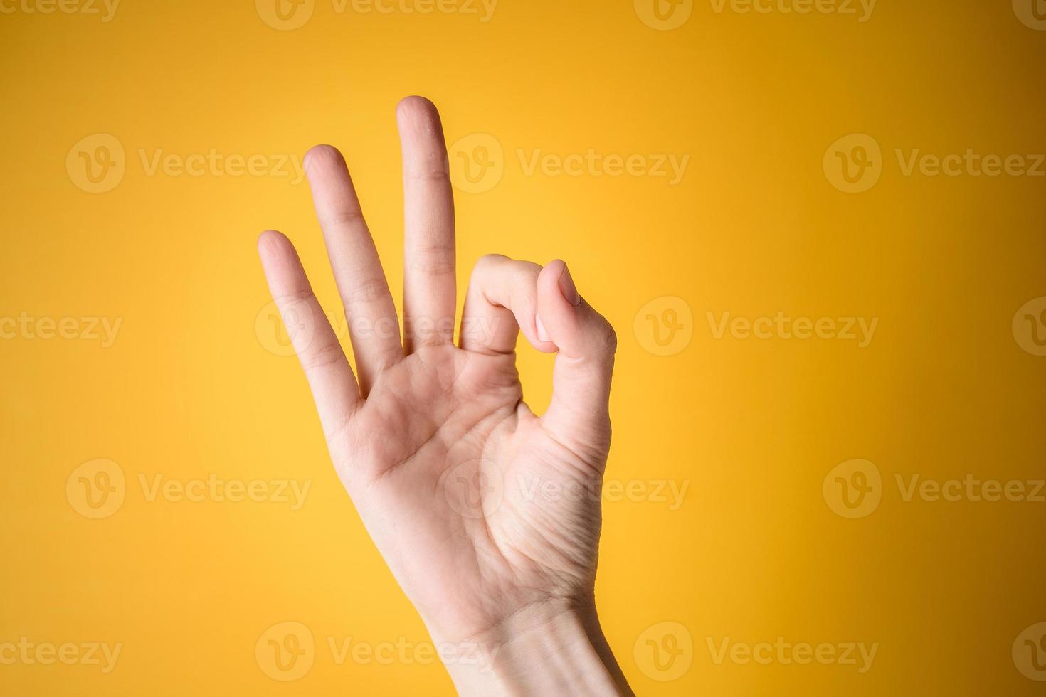 vrouw hand toont gebaar oke op gele achtergrond foto