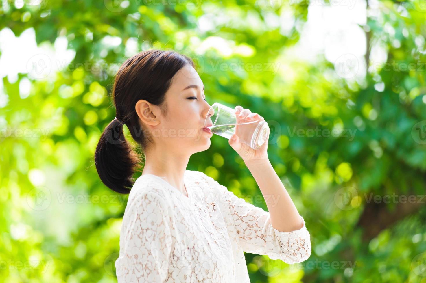 het Aziatische jonge meisje drinkt water foto