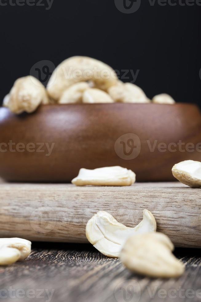 cashewnoten op een oude houten tafel en in een houten kom foto