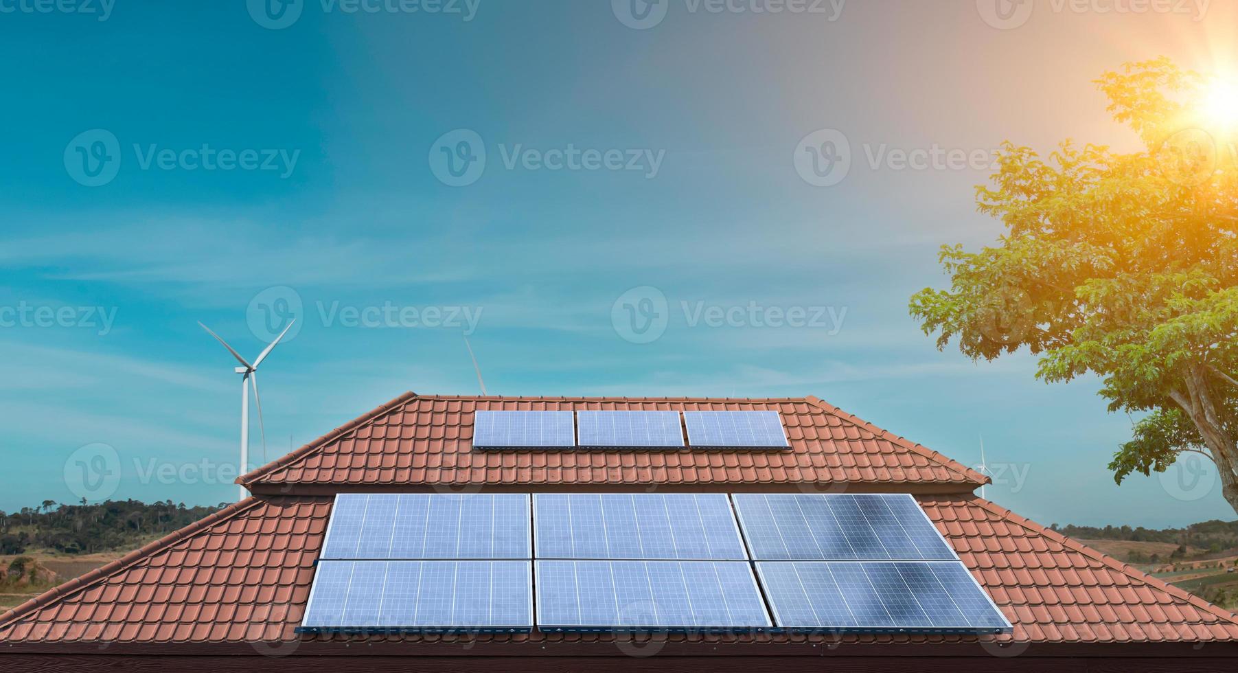 zonnepaneel op een dak van een huis met windturbines eromheen. fotovoltaïsche, alternatieve elektriciteitsbron. foto