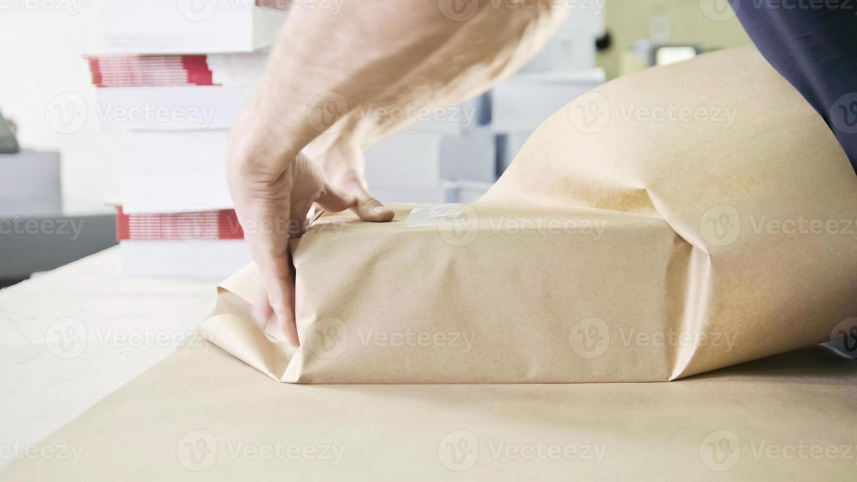 close-up van iemands handen die dozen met plakband in de grafische industrie verpakken foto