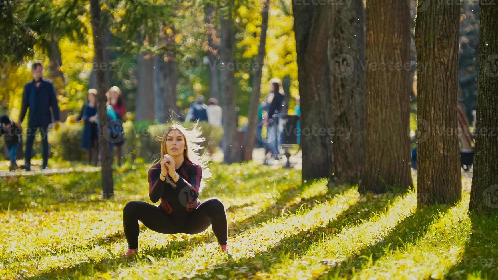 jong fitness vrouwelijk model dat traint in een weiland in het herfstpark, concept van sport buitenactiviteiten - squats foto