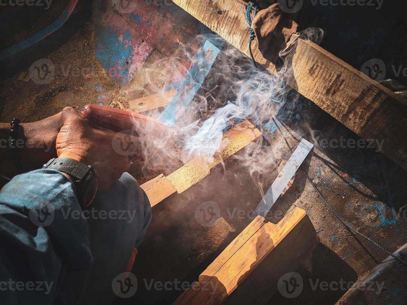 man boort ijzerhout in een boot foto