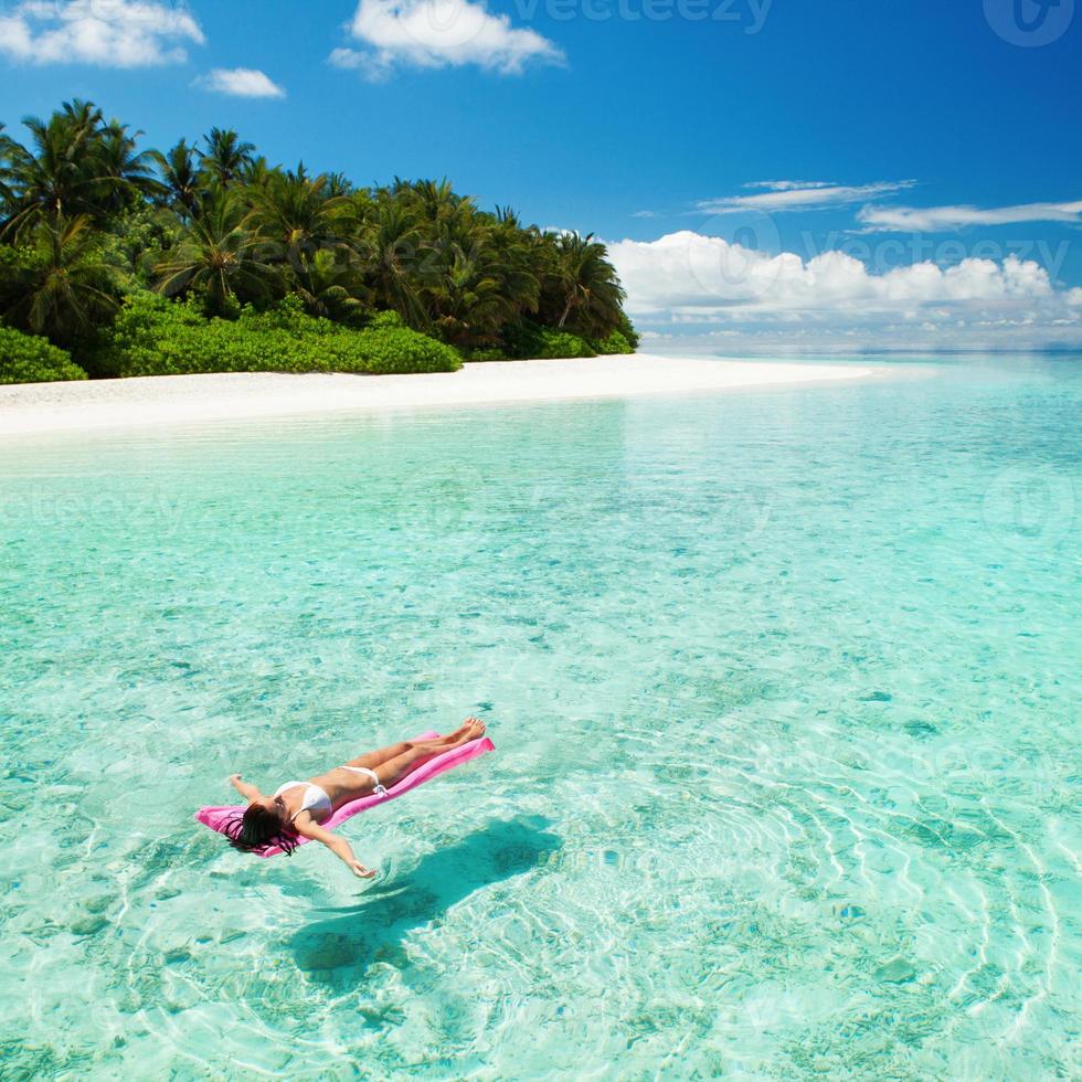 vrouw ontspannen op opblaasbare matras in de zee foto