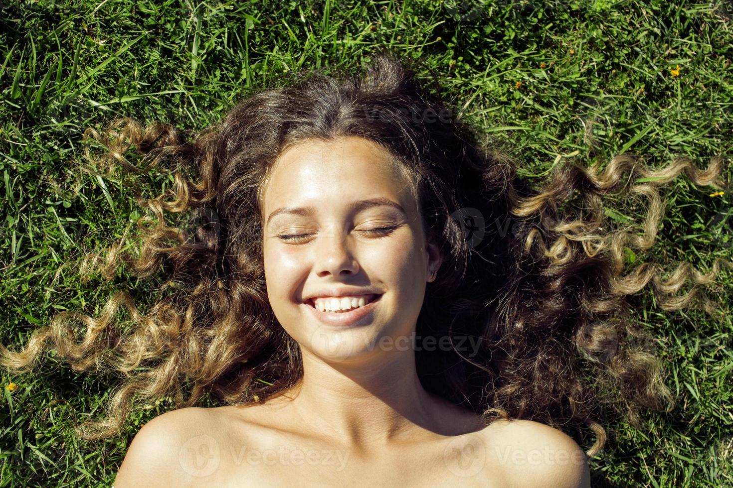 jonge schattige zomer meisje op gras buiten ontspannen glimlachen foto