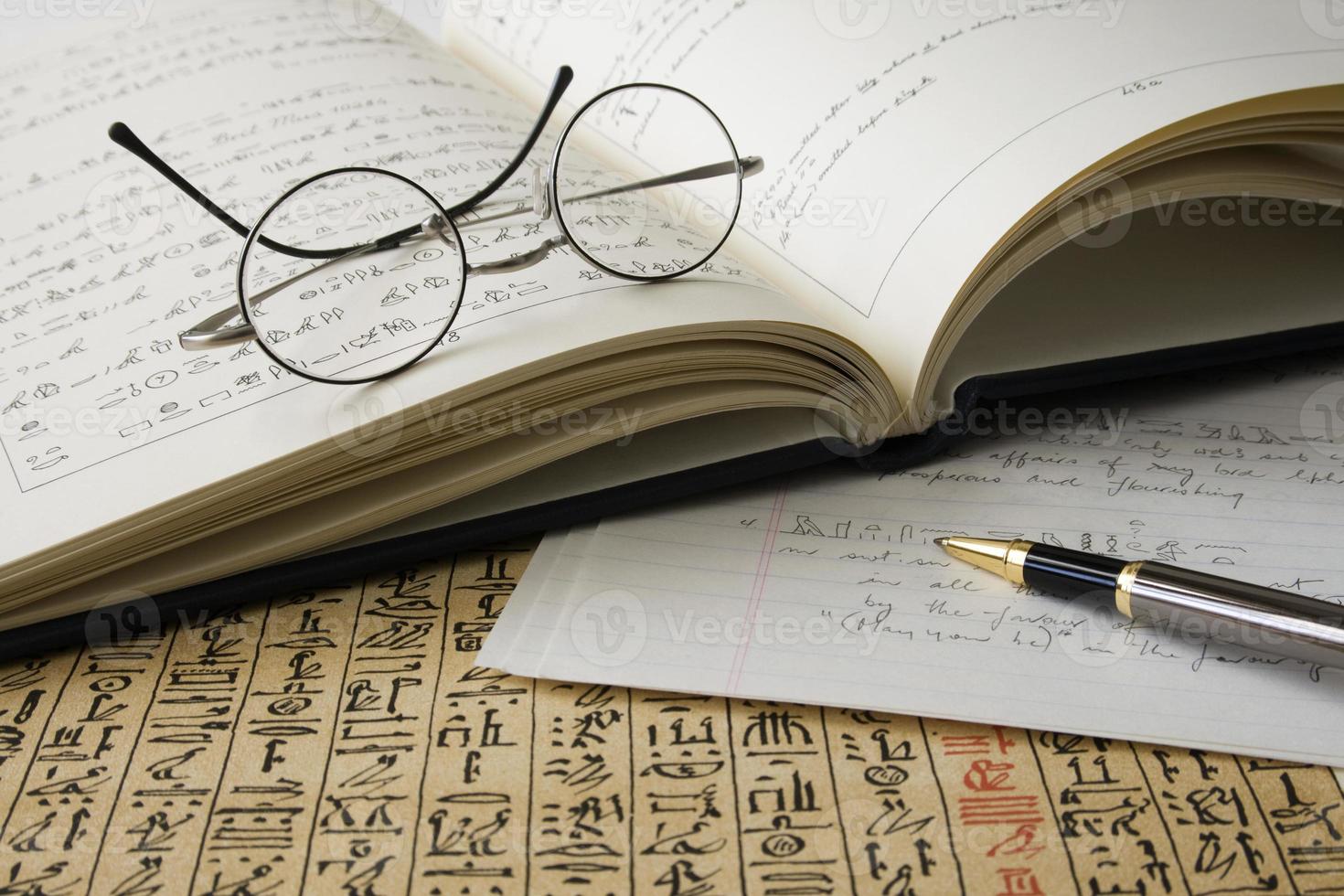 boek met hiërogliefen, papyrus, vertaling, bril en pen foto