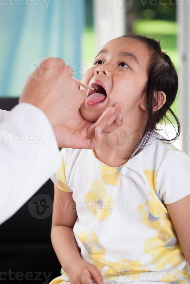 Aziatisch meisje tijdens keelonderzoek foto