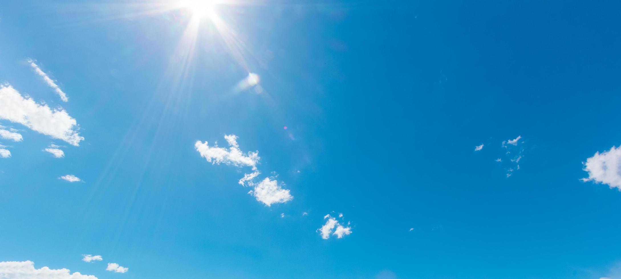 natuurlijke abstracte achtergrond van heldere blauwe lucht en pluizige witte wolken op een zonnige, licht een gloed en zon. foto