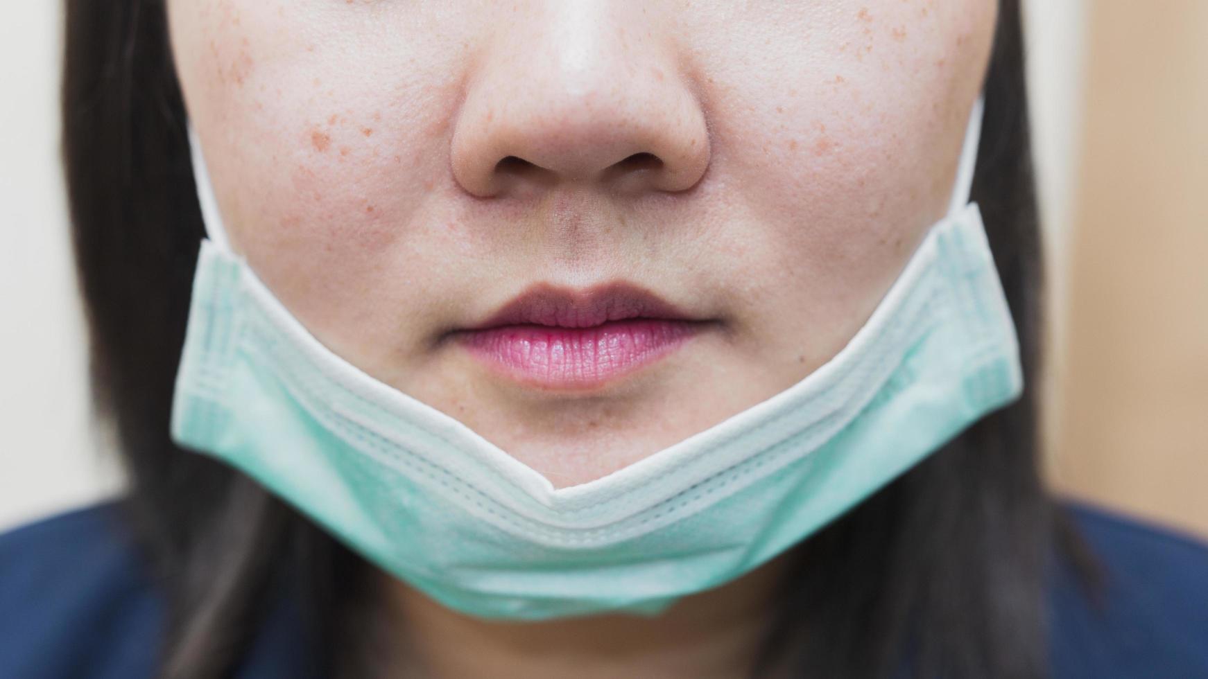 de foto met het halve gezicht van een vrouw die een masker onder haar kin draagt, is misplaatst om te dragen.