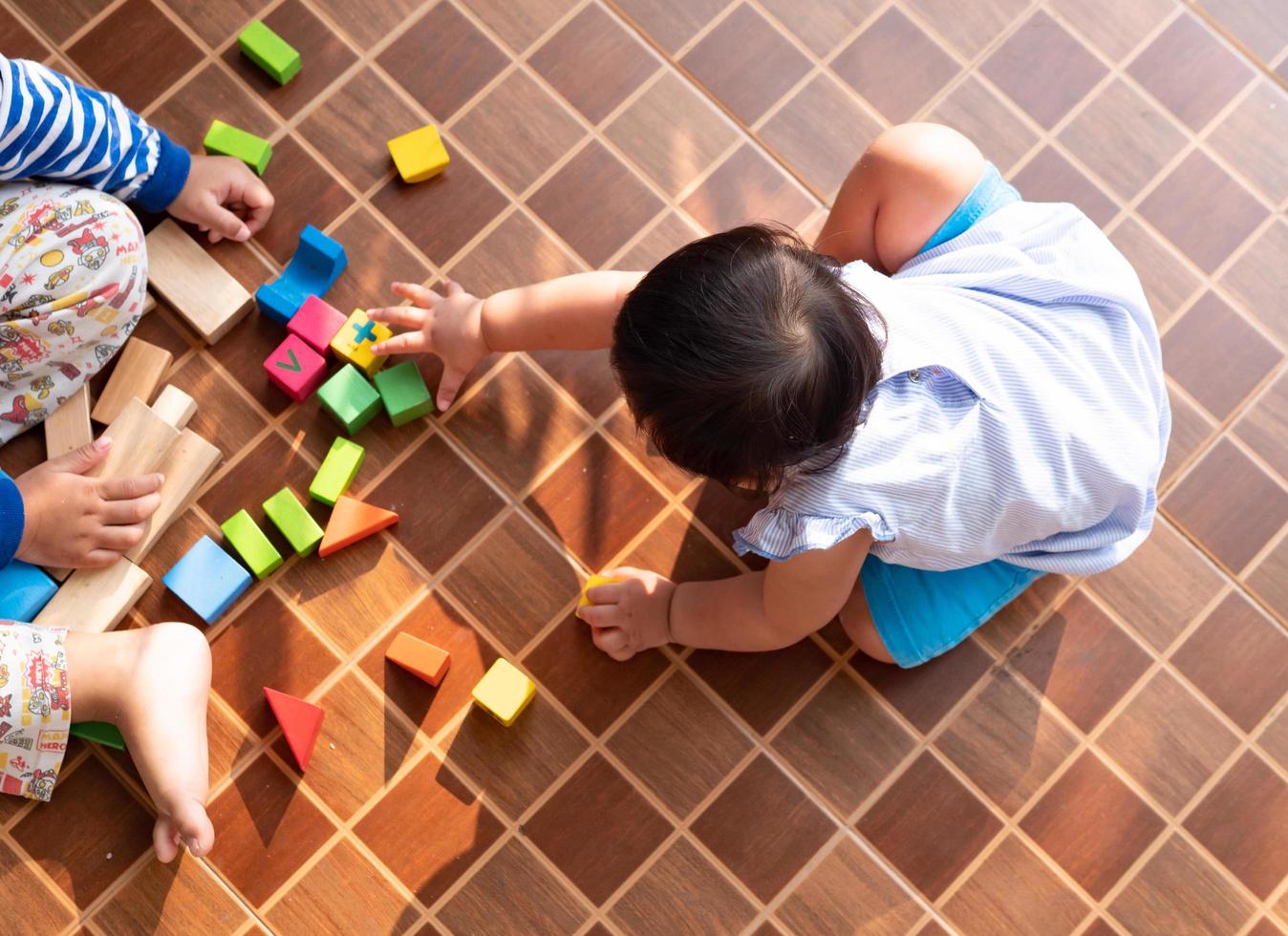 klein Aziatisch meisje speelt met houtblokken op de vloer foto