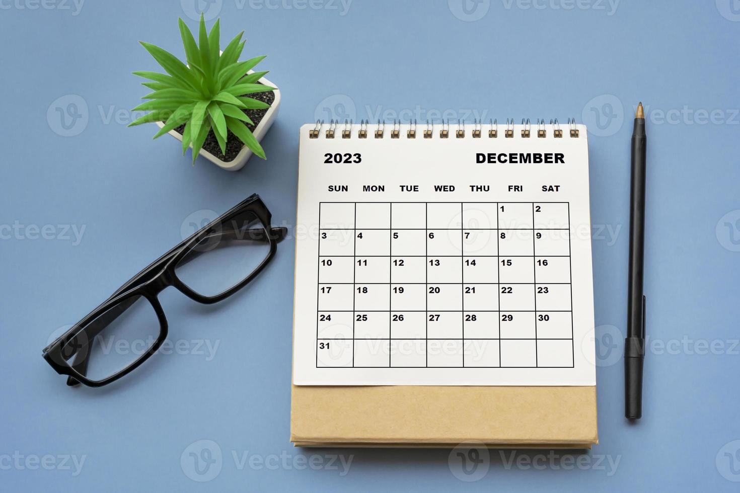 december 2023 bureaukalender op blauwe achtergrond. recht boven. plat liggen. foto