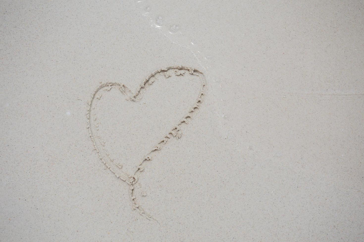 harten getekend op het zand van een strand foto