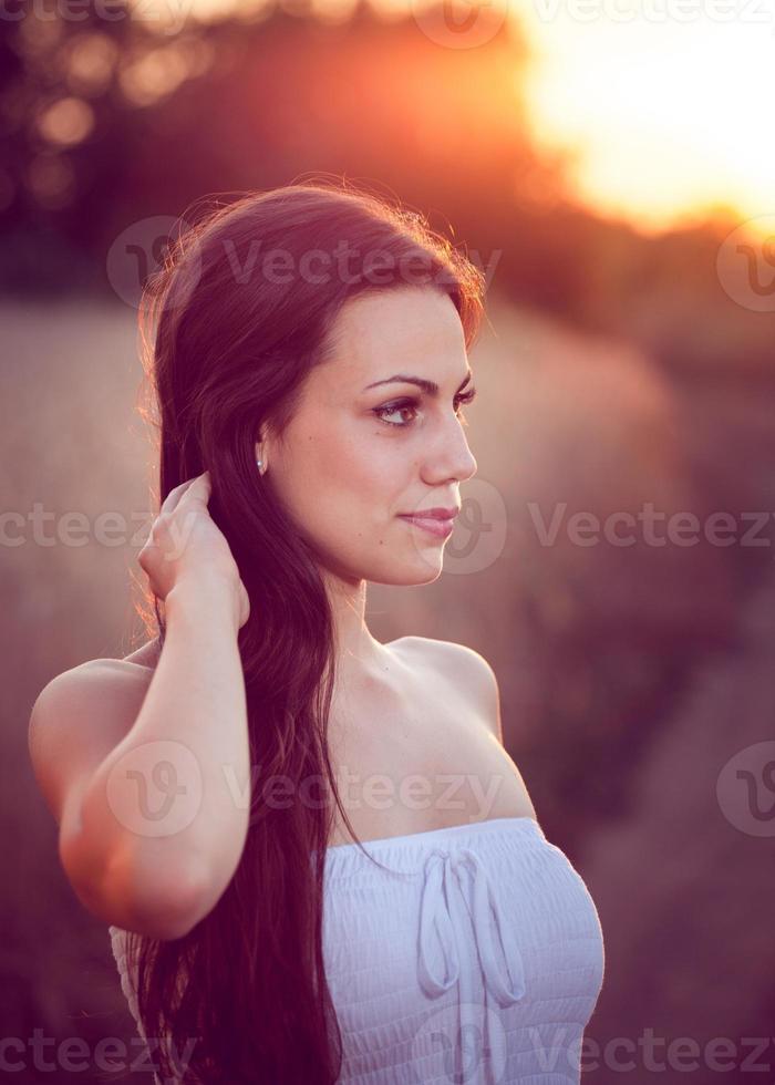 mooi meisje in een tarweveld bij zonsondergang foto