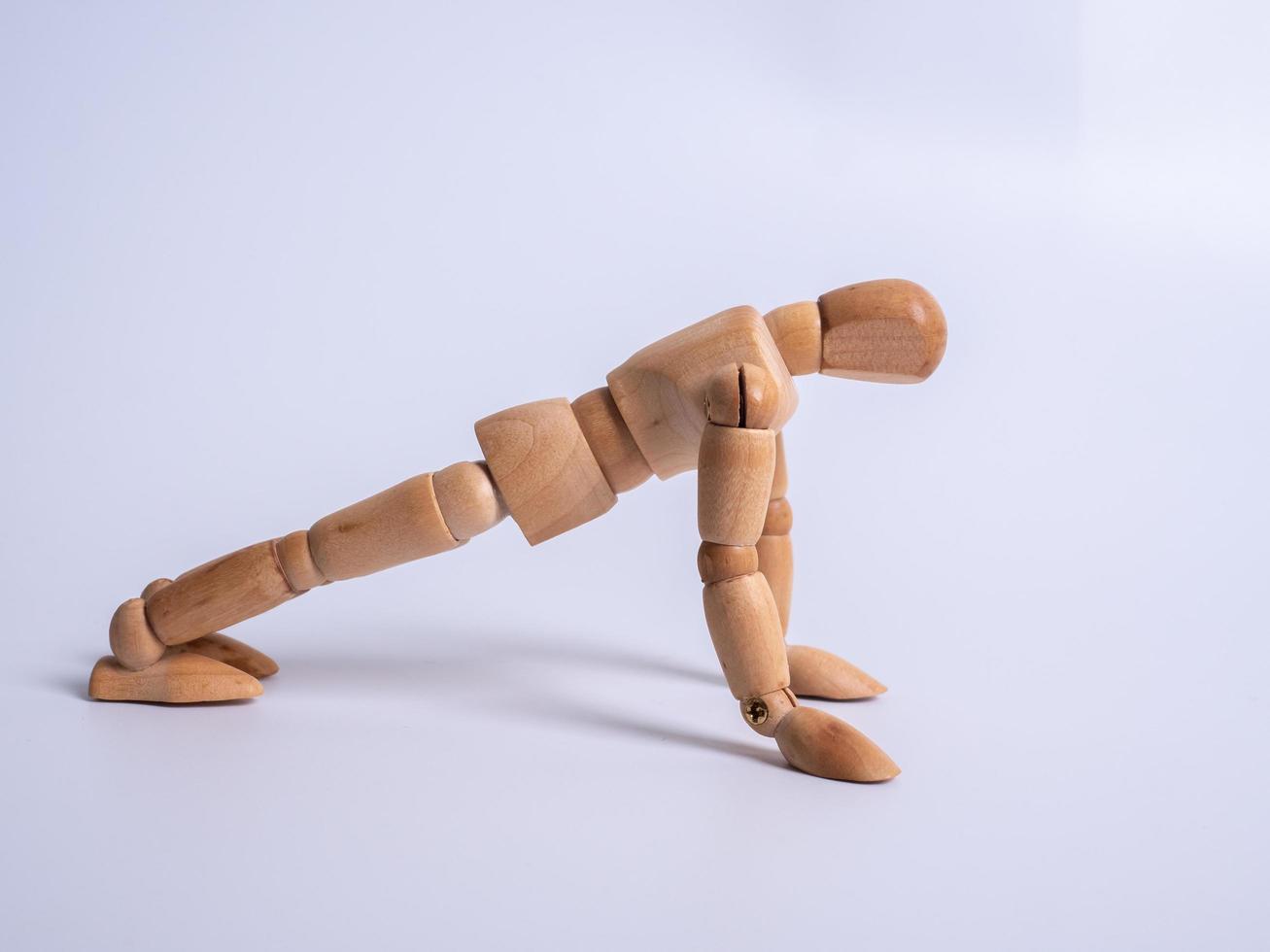 kleine houten pop tijdens push-ups op witte achtergrond foto