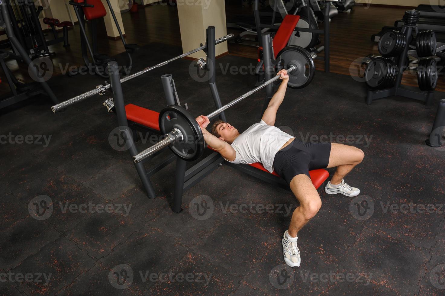 jonge man doet bench press training in de sportschool foto