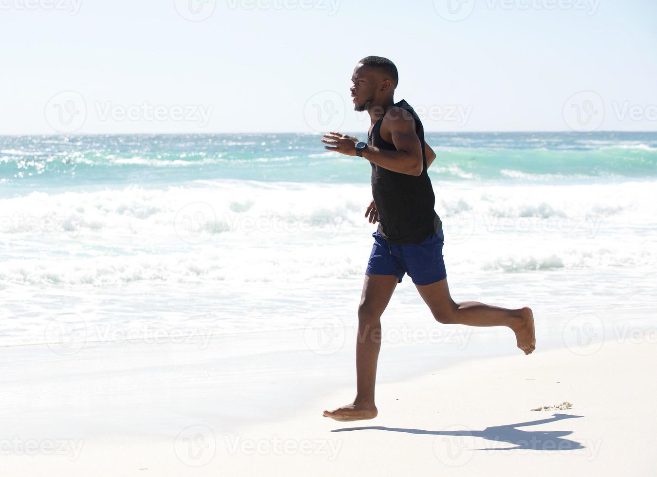 jonge man loopt op blote voeten op het strand foto