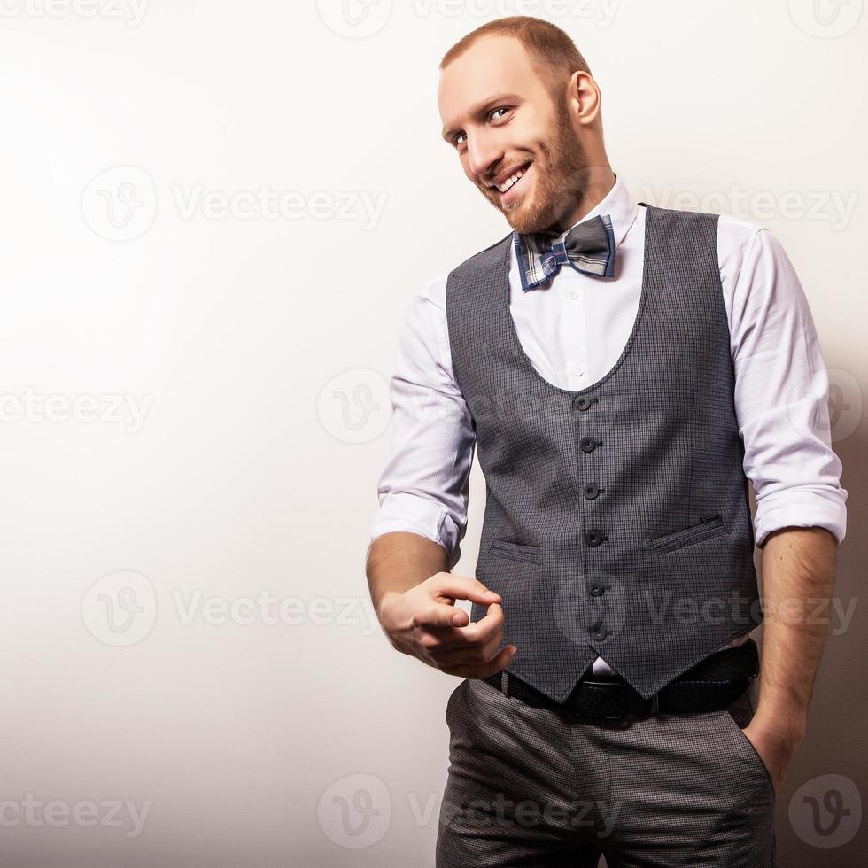 elegante jonge knappe man in grijs vest & strikje. foto