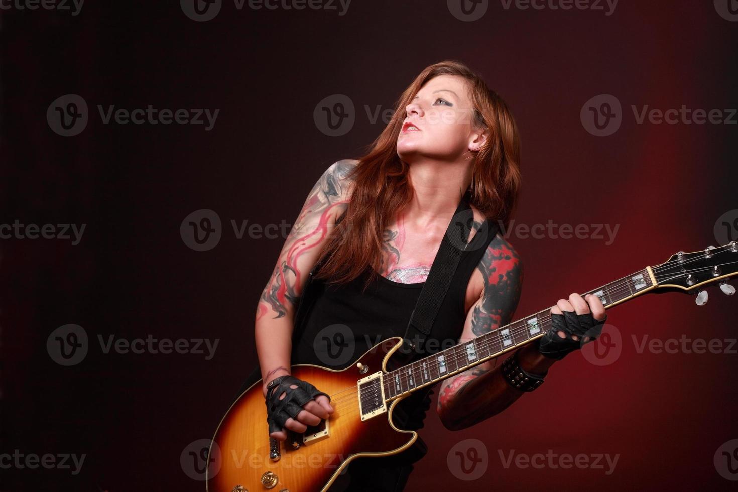 aantrekkelijk meisje met veel tatoeages die elektrische gitaar spelen foto