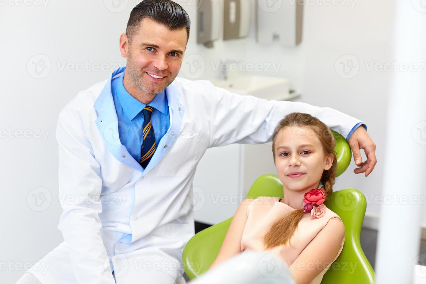 tandarts onderzoekt kleine meisjes tanden in de stoel van de tandarts foto