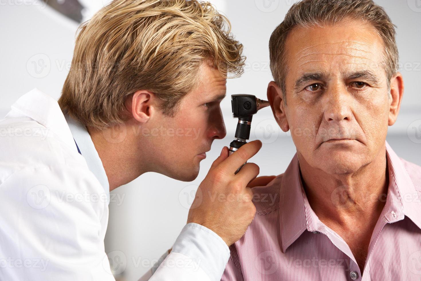 arts die de oren van mannelijke patiënt onderzoekt foto