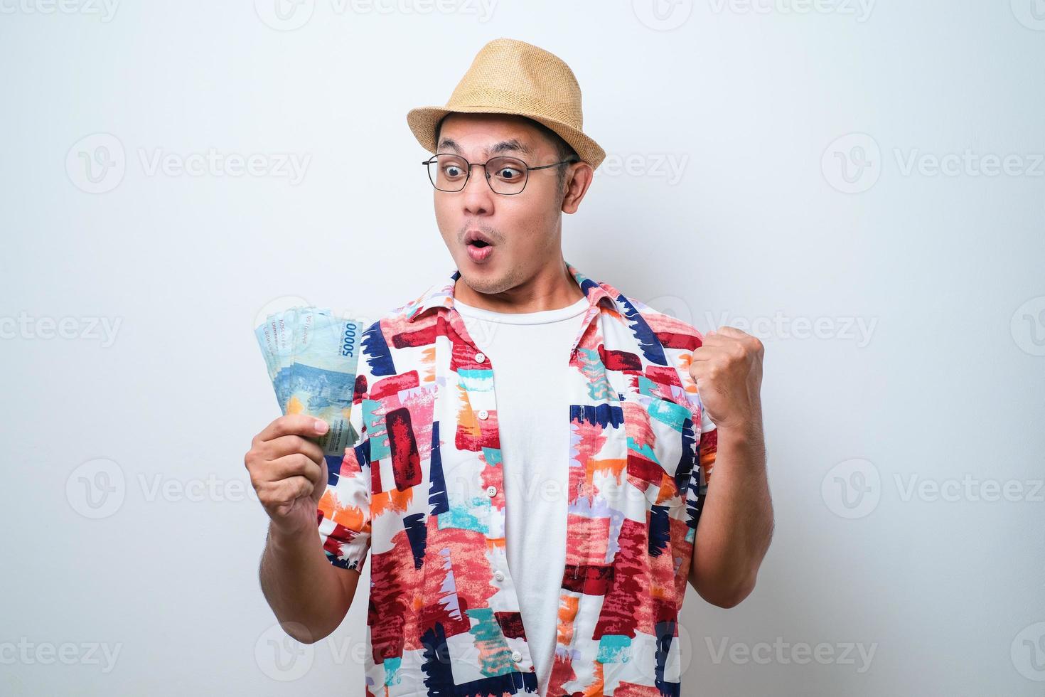 jonge aziatische man die opgewonden gezichtsuitdrukking toont terwijl hij geld vasthoudt foto