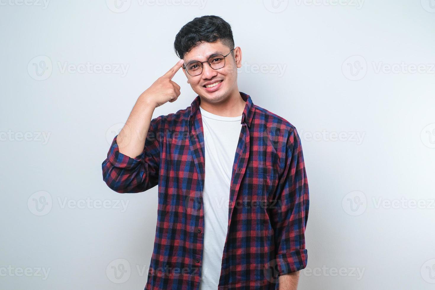 knappe jonge man met een casual shirt glimlachend wijzend naar het hoofd met de vinger van de hand foto