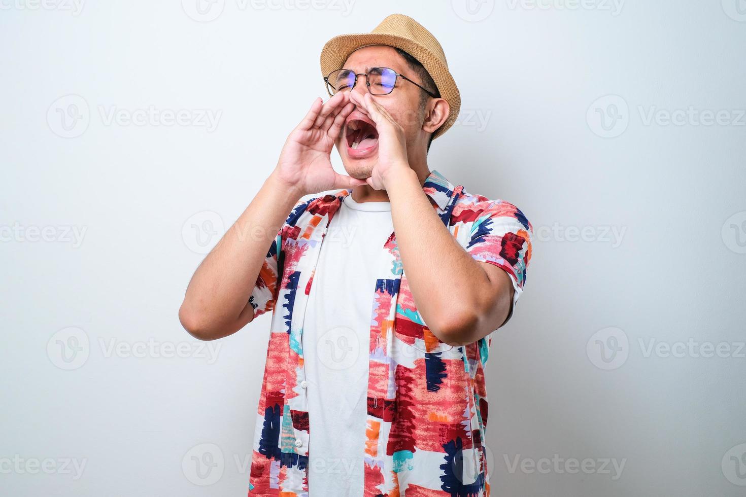jonge aziatische man schreeuwt en schreeuwt luid naar de kant met de hand op de mond foto