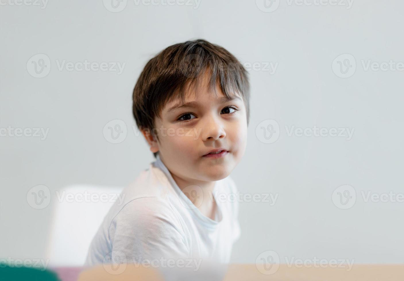 portret gelukkige jonge jongen die naar de camera kijkt met een lachend gezicht, kind ontspannen thuis in het weekend foto