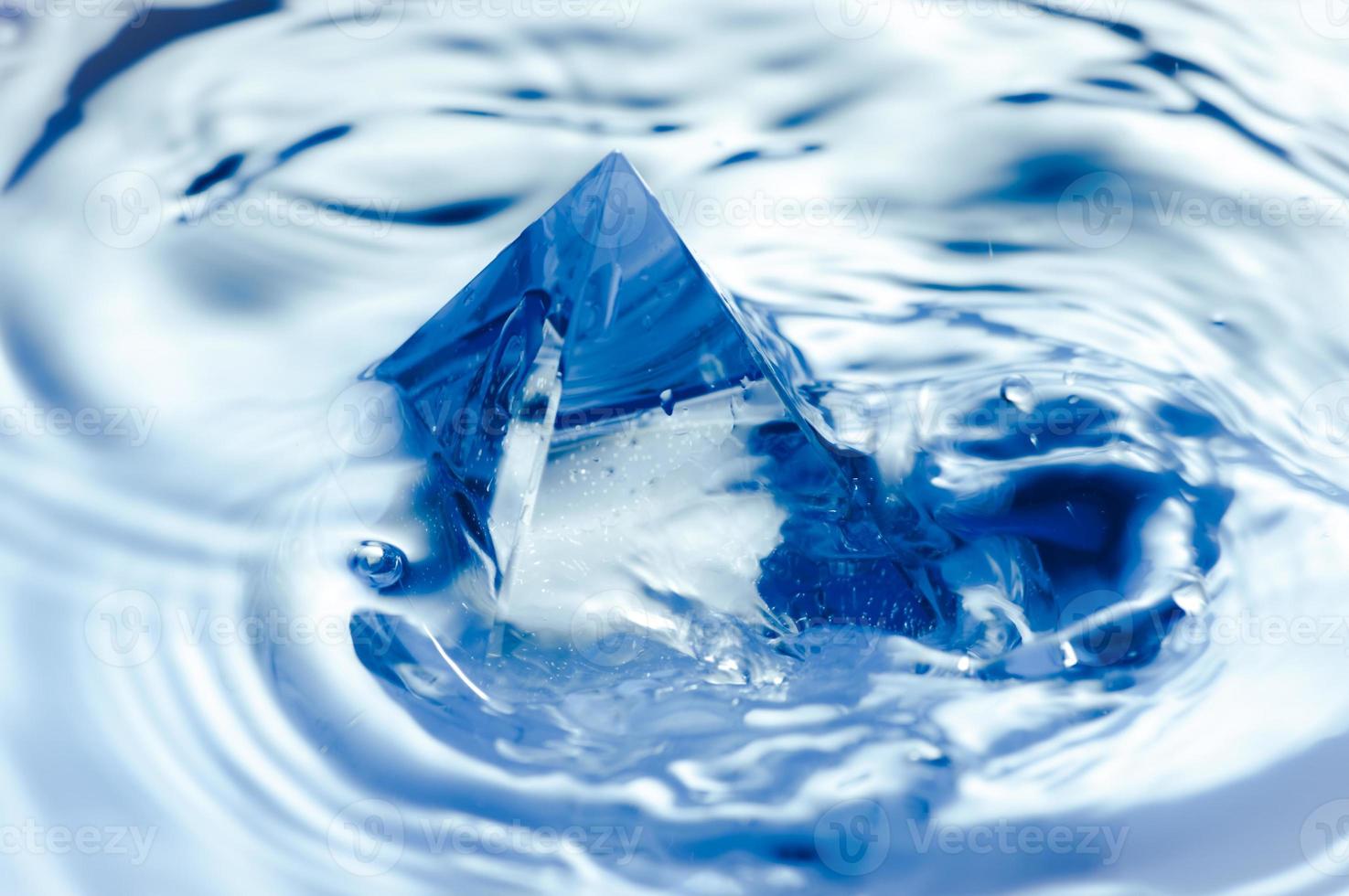 abstracte blauwe achtergrond met water splashen en een geometrisch object. piramide in het water. foto