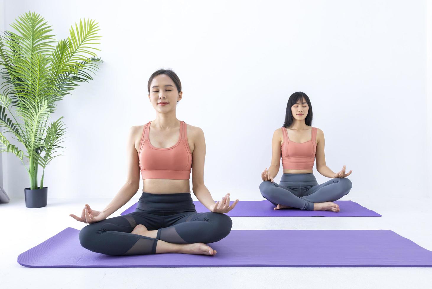 Aziatische vrouw die binnen yoga beoefent met een gemakkelijke en eenvoudige positie om het in- en uitademen in meditatiehouding te regelen foto