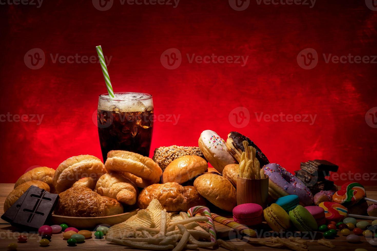 diverse soorten junkfood die gevaarlijk zijn voor de gezondheid op houten tafel met kopieerruimte rood licht achtergrond foto