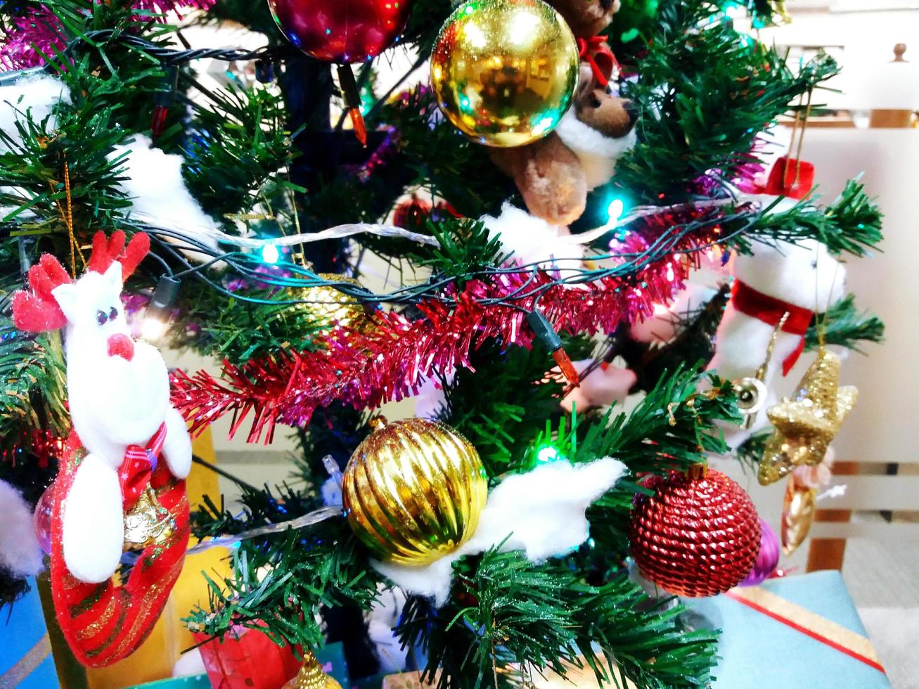 kleurrijke groene kerst en gelukkig nieuwjaar boomdecoratie met blauw licht, gouden bel, rode kerstman en bal soft focus foto