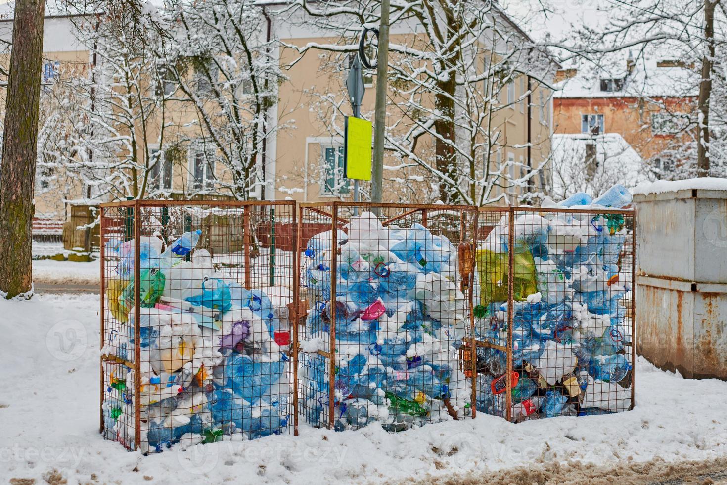 drie afvalcontainers vol plastic flessen, tassen en afval foto