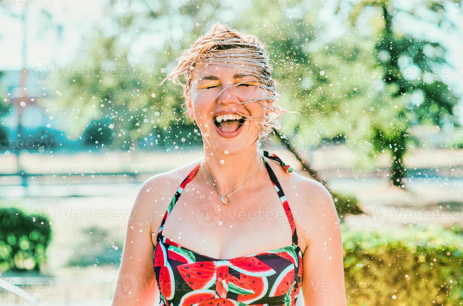 lachende emotionele blonde vrouw met nat haar die waterspatten maakt. vakantie, geluk, plezier, zomer, vrije tijd concept foto