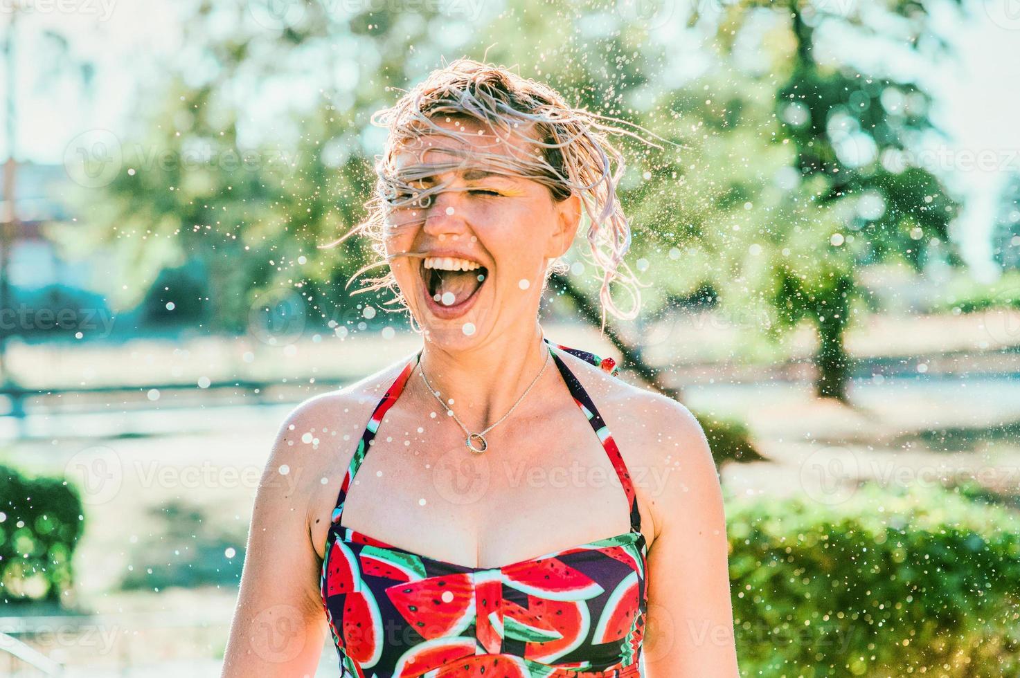 lachende emotionele blonde vrouw met nat haar die waterspatten maakt. vakantie, geluk, plezier, zomer, vrije tijd concept foto