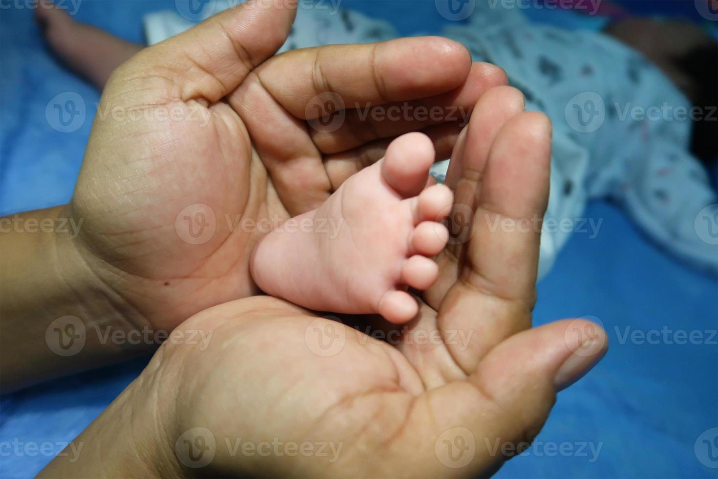 ouder houden in de handen voeten van pasgeboren baby. moeders hand die de voeten van haar baby bedekt. foto