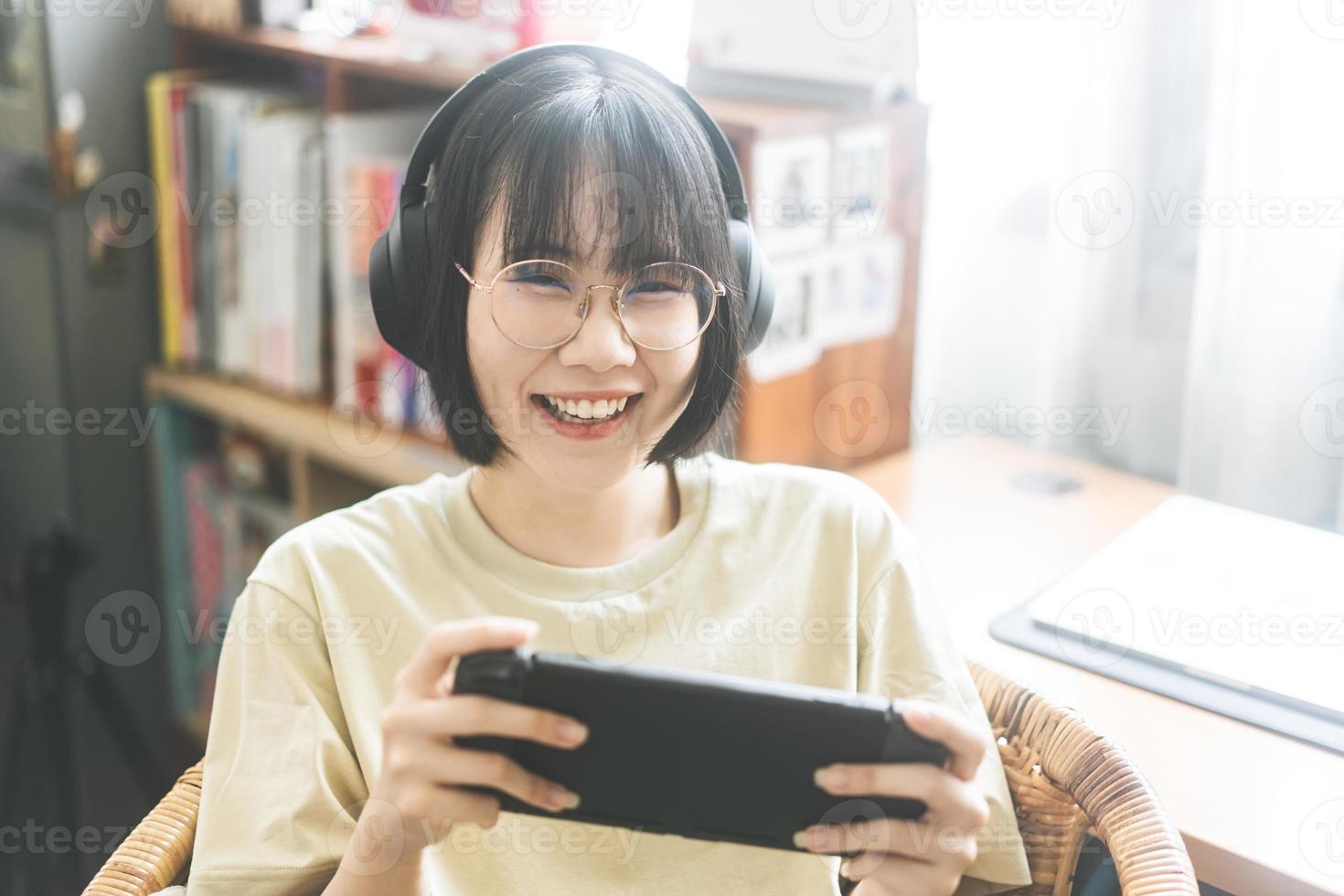 nerd-stijl jonge volwassen Aziatische gamer-vrouw draagt een bril en hoofdtelefoon speel een online game foto