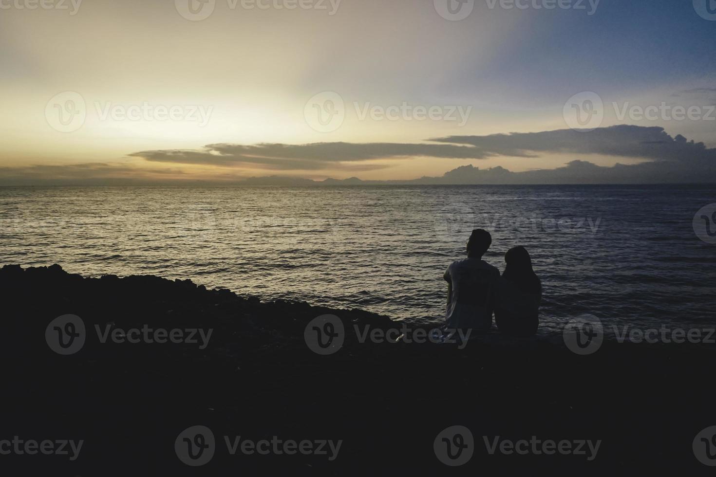 shilloutte van een romantisch stel daten op een strand tijdens een zonsondergang foto