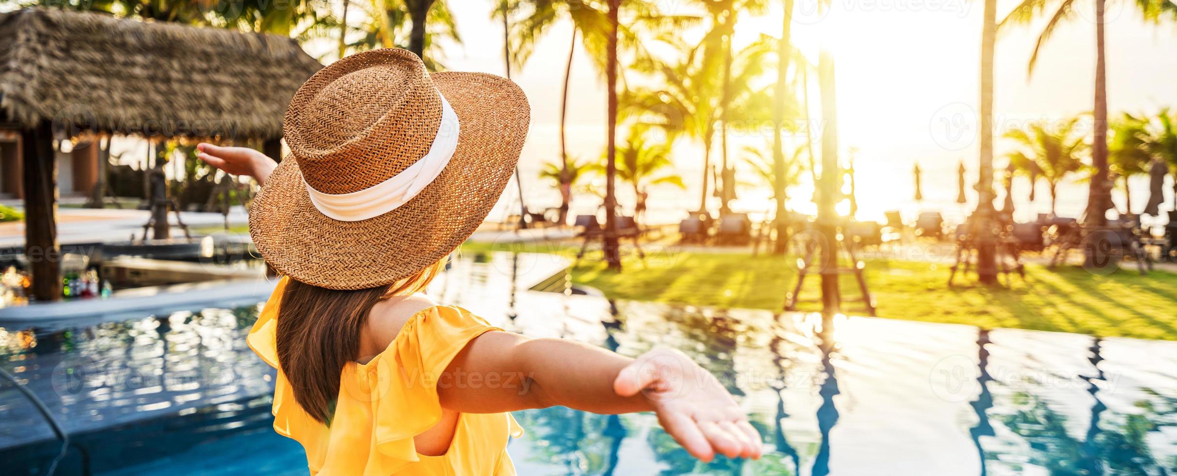 jonge vrouwelijke reiziger ontspannen en genieten van de zonsondergang bij een tropisch resortzwembad tijdens het reizen voor zomervakantie foto