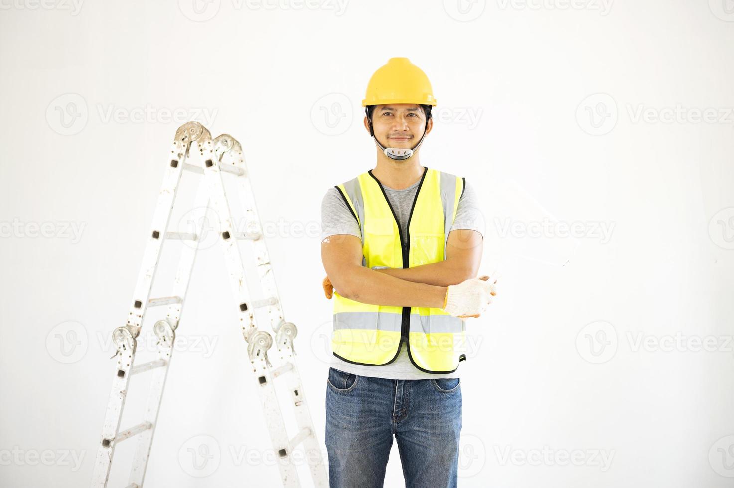 een aanzicht van de schilder achter de muur schilder met een verfroller en gespleten emmer op een grote lege ruimte met een houten trap. foto