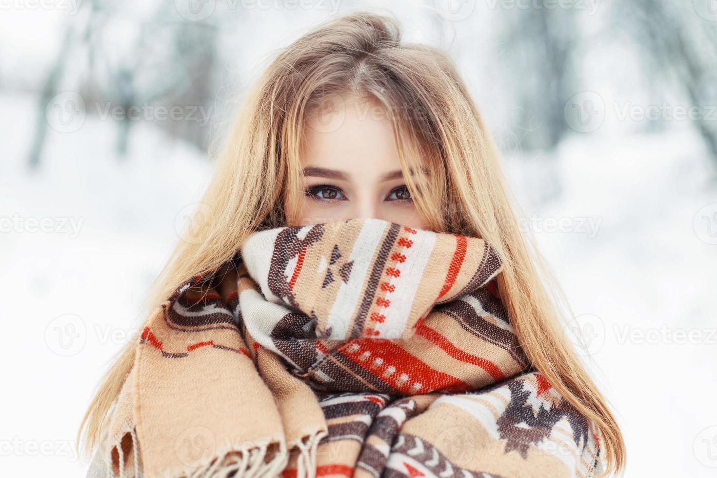 jonge gelukkige vrouw die winterdoek draagt. sjaal op het gezicht foto