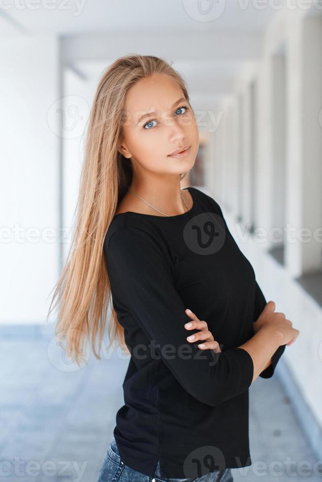 mooi meisje met blauwe ogen in zwart t-shirt op de achtergrond die vooruitzichten verlaat foto