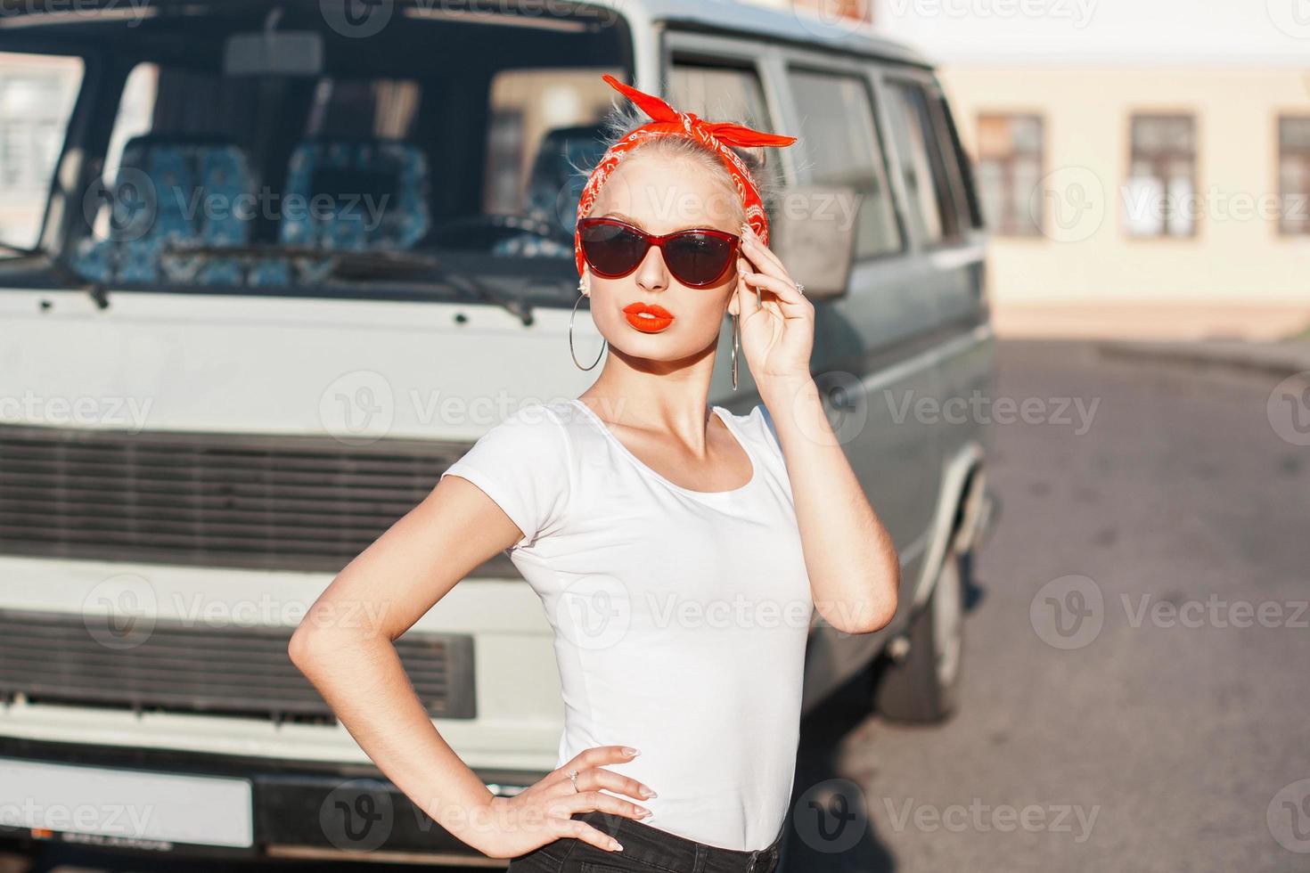 portret van een mooi hipstermeisje met zonnebril dichtbij de auto. foto