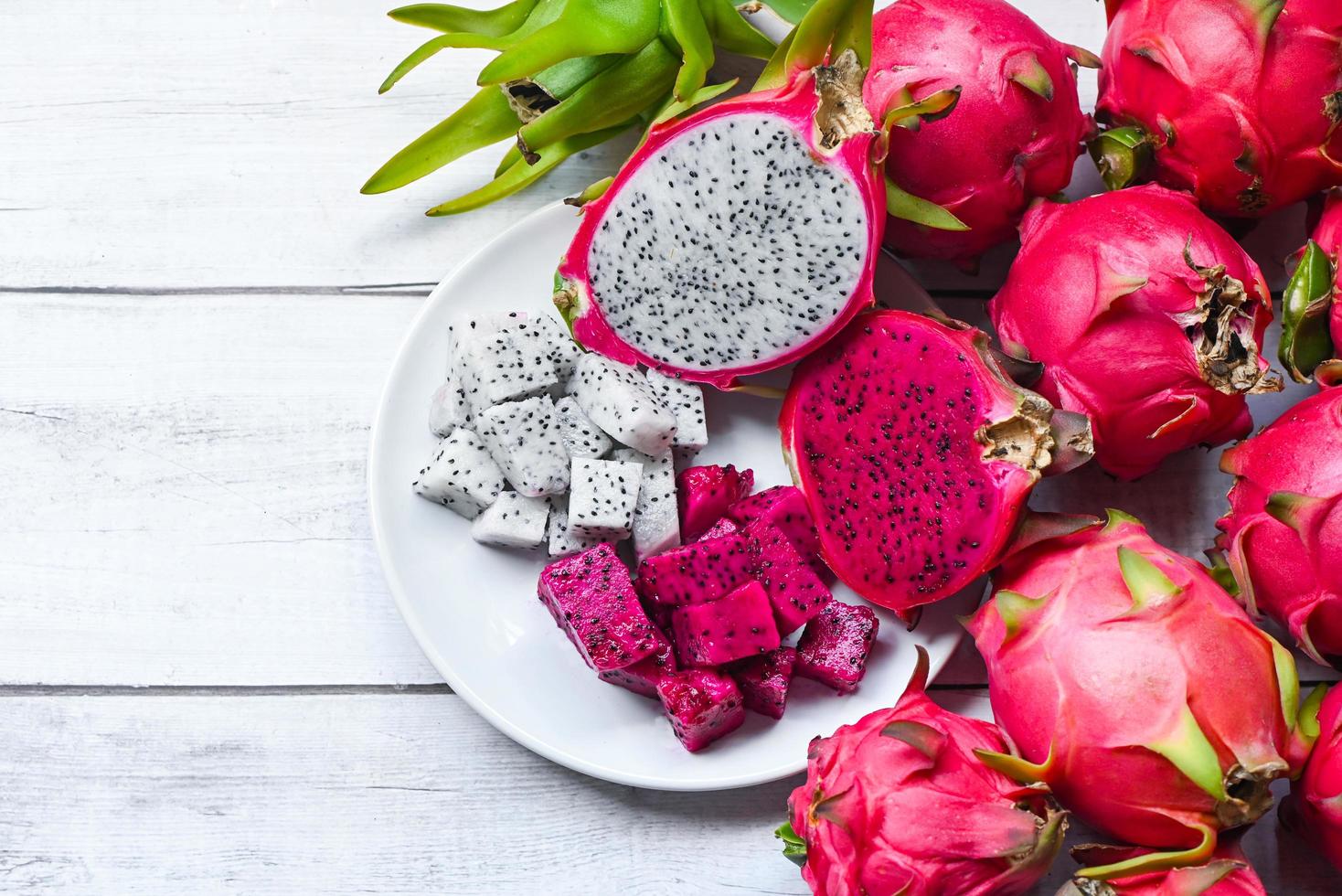 vers wit en roze rood paars dragon fruit tropisch in het aziatische thailand gezond fruit concept, dragon fruit slice en half gesneden op witte plaat met pitahaya achtergrond foto